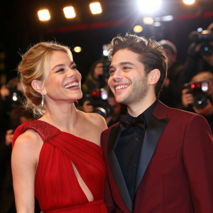 Sienna Miller and Xavier Dolan at a movie premiere. Formal attire, bright lights, paparazzi