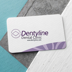 Creative digital design for a business card of Dentyline Dental Clinic, Medellin, Colombia. The card features a clean white background with a modern logo and text in gray and purple tones. The business card includes the brand name, clinic name, and website URL.