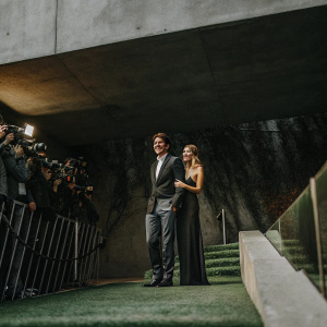 Jerry O'Connell and Giuliana Depandi at the Hollywood premiere. Gray concrete backdrop with paparazzi in the background.