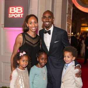 Mo Farah, Tania Nell, and an unnamed woman with their children Amani, Rhianna, Hussein, and Aisha. They are posing at a charity gala event. The background features a bold, neon BB Sport logo.