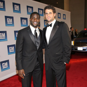 Reggie Bush and Matt Leinart attending a GM gala. Red carpet entrance, backdrop featuring GM logo. Both are in formal attire.
