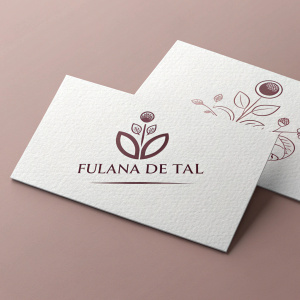 Business cards for Fulana de Tal, featuring a logo that resembles a seed. The design is minimalistic and elegant, with the company name and logo in bold letters on a white card, contrasting against a soft pink background. The cards also include social media icons.