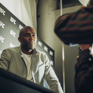 Anderson Silva, UFC fighter, in a promotional photo shoot. Intense gaze. Dark backdrop with UFC branding. Professional event setting