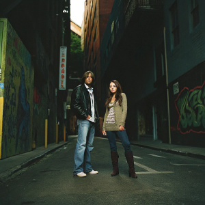 Billy Ray Cyrus and Miley Cyrus, styled for a magazine spread. Urban street scene, both look directly at camera