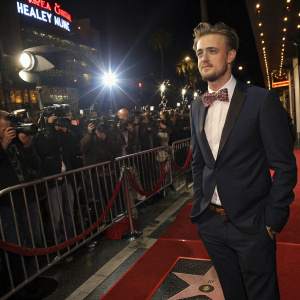 Boyd Holbrook, wearing a dark suit and a stylish bow tie, stands confidently on the Hollywood Walk of Fame under the bright lights and paparazzi flashes.
