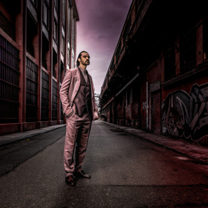 Zlatan Ibrahimovic, standing in a high-end men's fashion shoot. Urban street setting with graffiti walls.