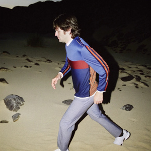 Sergi Roberto, in a vibrant blue and red jersey, strides energetically across the desolate, sandy wasteland. His intense stare locked onto a distant goal, his agile form barely discernible as a streak of speed.