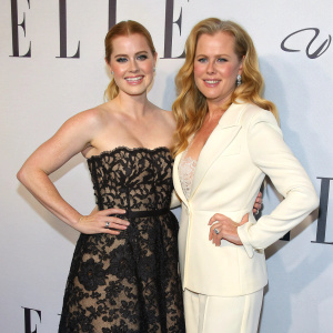 Amy Adams and Kathryn Adams attending the ELLE Awards, dressed in elegant attire. Amy in black lace gown, Kathryn in white suit. Posed against backdrop with ELLE logo, smiling