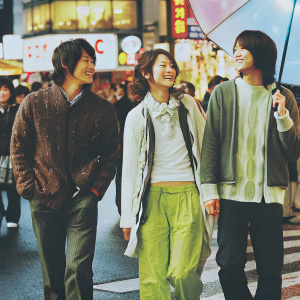Kim Si-Hoo, Yoona, and Jang Keun-Suk at a crowded street festival. They wear casual outfits. Neon signs and performers in background.