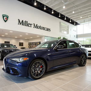 Dark blue Alfa Romeo Giulia Q4 parked at Miller Motorcars showroom. Dealership sign visible.