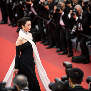 Fan Bingbing, Chinese actress, in a candid moment at Cannes Film Festival. Dressed in a black dress and a white scarf. Crowded red carpet event with flashing cameras.