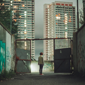 In the heart of a bustling metropolis, a decrepit gate and a wall adorned with vibrant graffiti marks the entrance to an enigmatic alleyway. A solitary figure stands at the gateway, against a backdrop of towering skyscrapers and neon lights, symbolizing a path to the unknown.