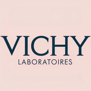 Vichy Laboratoires logo, simple and elegant. Serif font, dark and clean, centered on a pastel pink background.