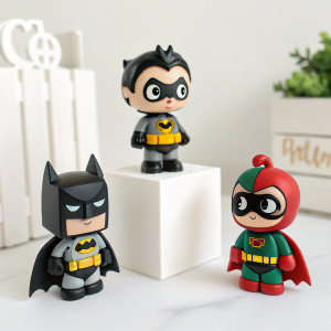 Display of miniature Batman Li'L Gotham figures. White backdrop. Batman, Harley Quinn, Robin in various playful poses.