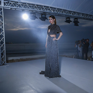 Blanca Suarez in a bold ensemble. Striking pose at the Cannes Film Festival. Black and white polka dot dress with asymmetric hemline. Dimly lit stage with paparazzi flash bulbs popping