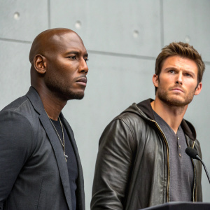 Tyrese Gibson and Scott Eastwood at a press conference. Intense look, gray backdrop, minimal setup.
