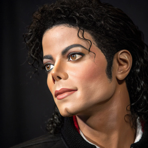 Lifelike wax statue of Michael Jackson. Dark background. Detailed close-up of face and upper body.
