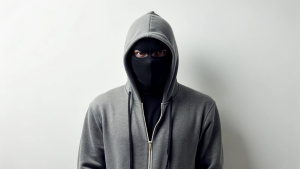 An underground director with a black mask without a face in a gray hoodie on his head stands on a white background