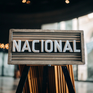 Modern TV logo design featuring the name 'Nacional'. Bold sans-serif font, set against a bright green backdrop.