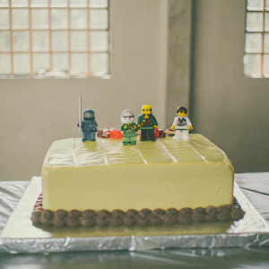 A stunning Lego Ninjago themed birthday cake for Luca's 7th celebration. Vibrant colors and detailed Ninjago characters. Characters and elements from Ninjago universe. Shiny flat surface, characters arranged around cake. Photo focuses on the elaborate cake design.