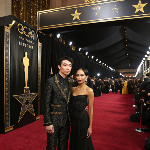 Ezra Miller and Zoë Kravitz attending a glamorous premiere. Black and gold themed venue, star-studded crowd