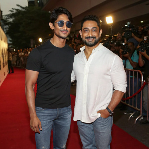 Prateik Babbar and Aamir Khan attending premiere event for their new film. Prateik in black t-shirt, sunglasses, and jeans, Aamir in white shirt and jeans. Red carpet with enthusiastic crowd and photographers.