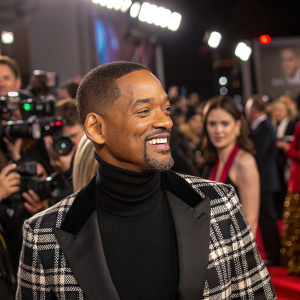 Will Smith at the star-studded gala. Wearing a black turtleneck and plaid jacket. Crowded event, flashing cameras