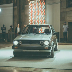 A sleek, customized Volkswagen Golf Mk2 at the vintage car rally. Featured on the main stage with a vibrant banner backdrop.