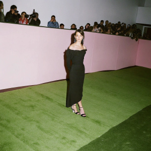 Maia Mitchell, wearing an elegant off-shoulder black dress, at the Hollywood premiere of Disney's 'The Lion King'. Crowd and flashing cameras in background