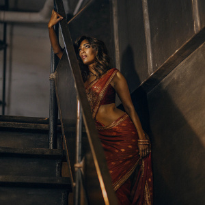 Chitrangada Singh, draped in a vibrant red saree with golden embroidery, posing elegantly at the Filmfare Awards. Dark, dramatic backdrop