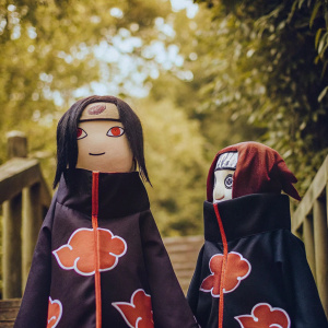 A digital illustration featuring Naruto Shippuden characters in chibi style. They are dressed in Akatsuki robes with red symbol patterns. Dark color palette with red highlights. Against a simple white backdrop.