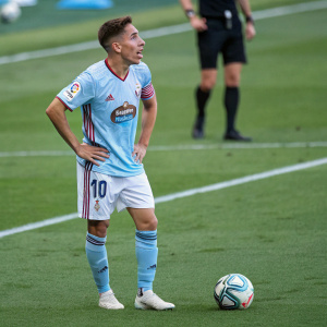 Emre Mor, soccer player, in a grimace, wearing the RC Celta jersey. Pitch background, soccer ball at his feet