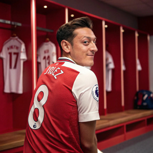 Mesut Ozil, wearing Arsenal's jersey with number 8, poses for a photo in the team locker room.