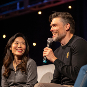 Darah Trang and Anson Mount at a Star Trek panel. Dark, theater style background. They stand next to each other, both smiling warmly.