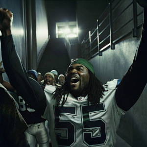 Jaylon Smith, African American football player, with dreadlocks and green cap. Wearing Dallas Cowboys jersey number 55. Celebrating victory on field surrounded by teammates.