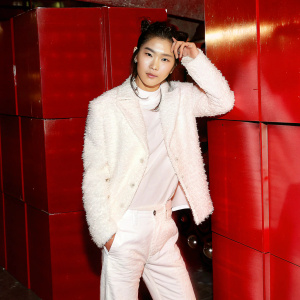 Zhang Yifan, a member of BonBon Girls 303, with a casual, cool pose in a modern outfit. Large, colorful geometric shapes form the backdrop