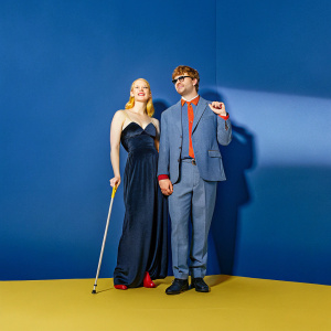 Deborah Ann Woll and E.J. Scott at a premiere event. Woll in black gown, Scott in gray suit with red accents. Both stand in front of a Netflix backdrop.