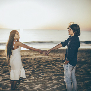 Ariana Grande and Dalton Gomez standing at the beach. Sunset in background, no kiss