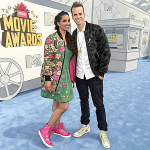 Lilly Singh and Jerome Jarre at the annual MTV Movie Awards. Pink sneakers, floral jacket, green dress, white shirt, black jacket. Blue carpet.