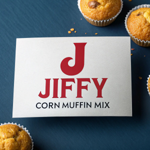 Modern logo design for Jiffy Corn Muffin Mix. Prominent letter J in sleek, bold font. Brand name in red letters beneath. Product description in smaller text. Dark blue background.