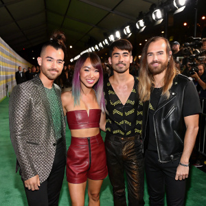 DNCE band members, Cole Whittle, JinJoo Lee, Joe Jonas, Jack Lawless, posing at award show. Green carpet, paparazzi in background