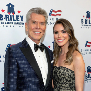 Michael Buffer and Christine Buffer, smiling, attending the annual gala event. They are standing in front of a backdrop with B Riley Co. and Sugar Ray Leonard Foundation logos. Both are dressed in formal attire.