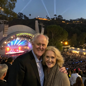 John Lithgow and his wife at the Hollywood Bowl, celebrating the opening night of 'The Producers'. Crowds and illuminated lights surrounding them.