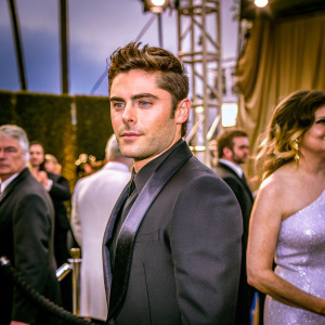 Zac Efron, wearing a sleek black suit, stands out at the awards ceremony.