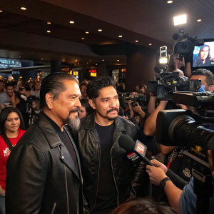 Yadi Valerio Rivera and Emilio Rivera attending a bustling press conference for 'Mayans M.C.' Season 2 debut. Crowded venue with flashing cameras and microphones