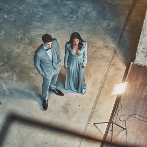 Grant Gustin and Chloe Bennet at the award show. Both dressed formally, Grant with slicked-back hair, Chloe with flowing dark hair. Simple black background, spotlight on them.