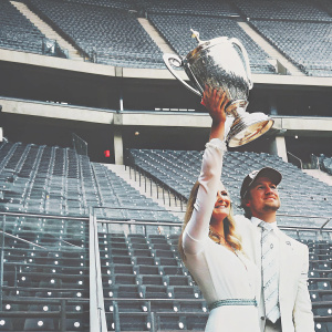 Nico Rosberg and Vivian Sibold celebrating with a grand trophy. Empty stadium in the background.