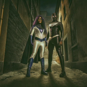 Two superheroes from Marvel Comics. One with long dark purple hair, white and blue costume. Standing beside masked hero in bold pose. Dark urban alleyway background.