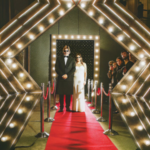 Amitabh Bachchan and Shweta Nanda at award ceremony, standing on neon-lit carpet. Amitabh in sleek black suit, Shweta in elegant white gown, against star-studded backdrop.