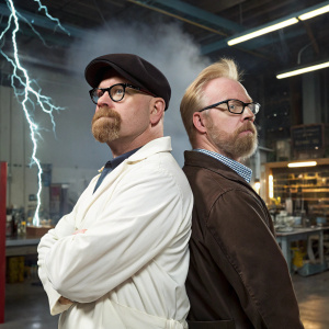 Promotional poster for MythBusters Season 3 featuring Jamie Hyneman and Adam Savage. The background showcases a laboratory setting with various scientific equipment and experiments in progress.